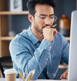 Businessman sits thinking at his desk monitor