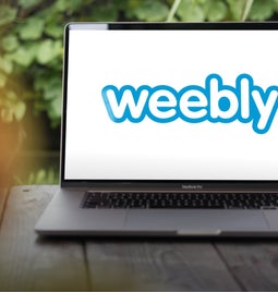 Laptop sits on a table outside displaying the Weebly logo