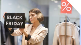 Shop owner places a Black Friday sign in the window, with sale sign visible in the background