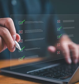 Businessman working on laptop computer comparing checklists