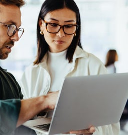 Man and woman discussing in front of a laptop