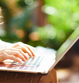 Lady types on her laptop on a sunny day