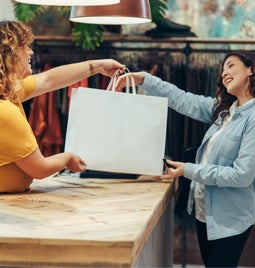 Smiling shop owner hands a large bag to a happy customer