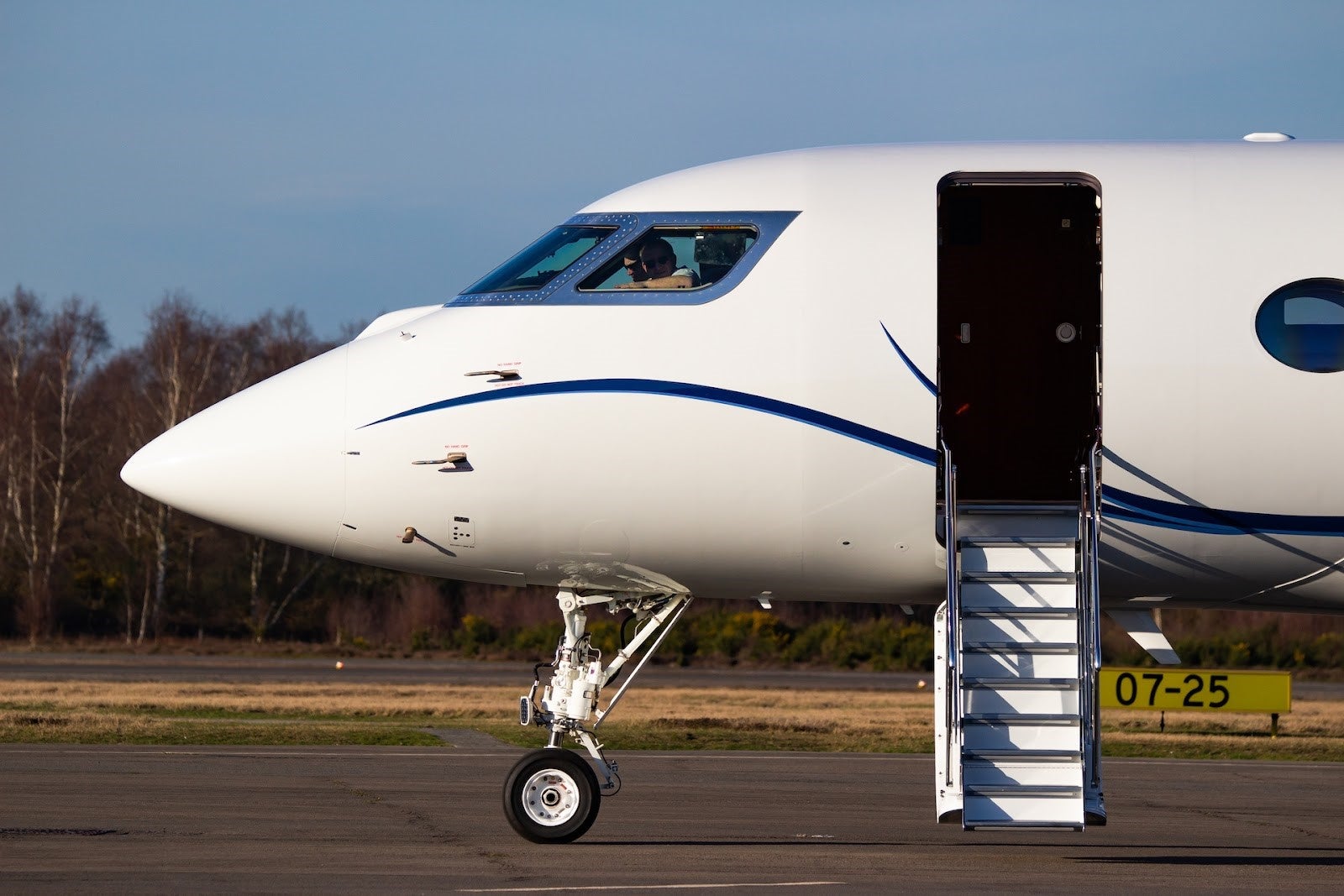 the cockpit of a hit private jet on a runway with stairs leading inside