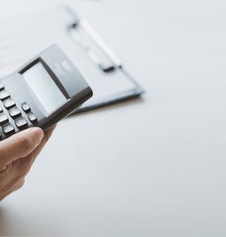 Hands using a calculator against a white backdrop