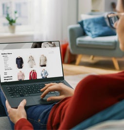 Screenshot of a woman with a laptop on her lap looking at an ecommerce store.