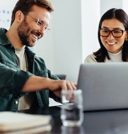 Two people smiling over a laptop